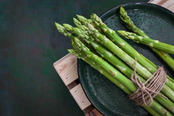 istock Raw fresh asparagus on rustic green background 1328850704