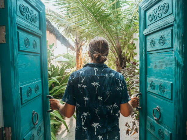 uomo che apre le porte della villa sulla spiaggia di lusso - luxury hotel palm tree lush foliage asia foto e immagini stock