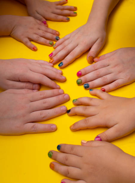 istock Multi-colored kids manicure on yellow background. Close up 1328851069