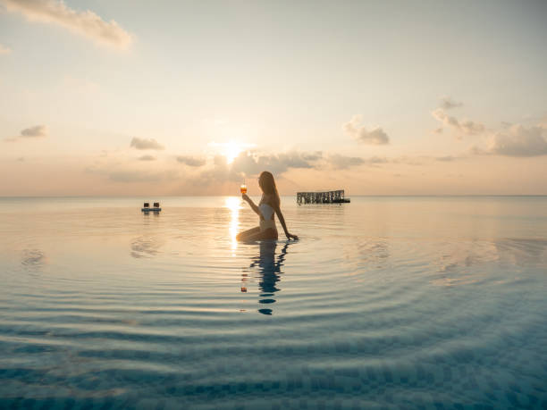 istock Woman drinking cocktail at sunset in an infinity pool 1328852008