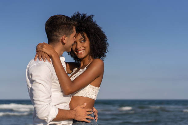 istock Multiracial young couple embracing on the beach 1328852200