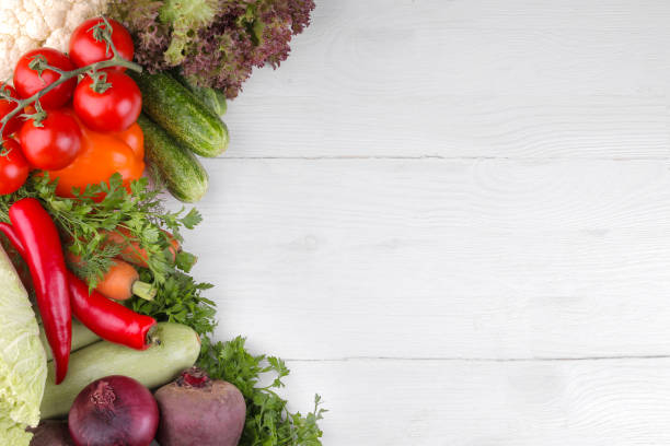 istock Many different vegetables include beets, cabbage, zucchini, carrots, tomatoes, peppers, onions, garlic, and cucumbers and lettuce on a white and wooden background. top view 1328853258