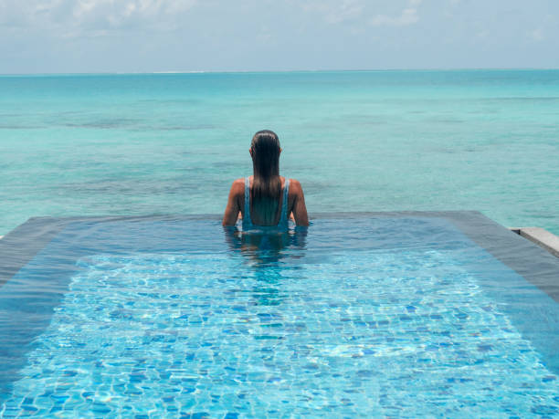istock Young woman in an infinity pool over tropical lagoon 1328853710