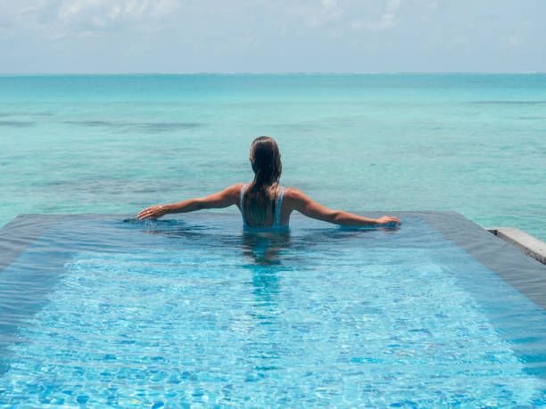 istock Young woman in an infinity pool over tropical lagoon 1328853715