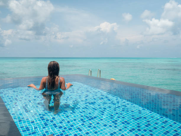 istock Young woman in an infinity pool over tropical lagoon 1328853724