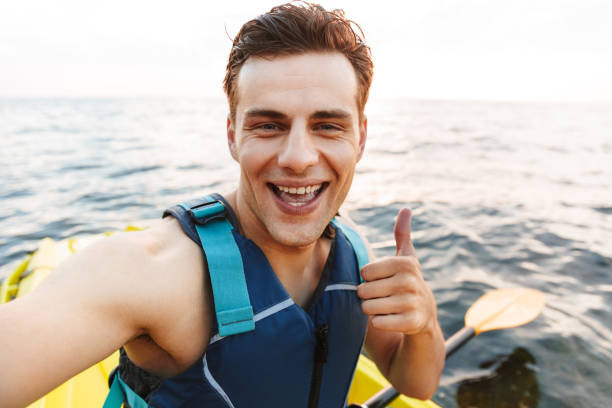 przystojny człowiek spływy kajakowe na morzu jeziora w łodzi zrobić selfie przez kamerę. - rowboat nautical vessel river mid air zdjęcia i obrazy z banku zdjęć