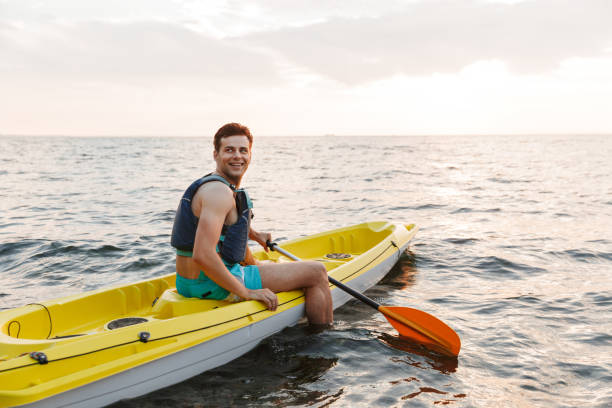 istock Handsome man kayaking on lake sea in boat. 1328858056