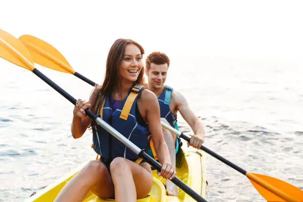 Beautiful young couple kayaking on lake together and smiling