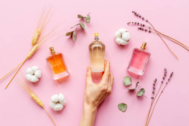 istock Hand holds perfume bottle with flowers flat lay 1328859906