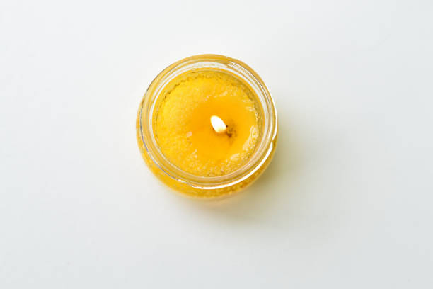 A yellow lit candle in a jar, top view
