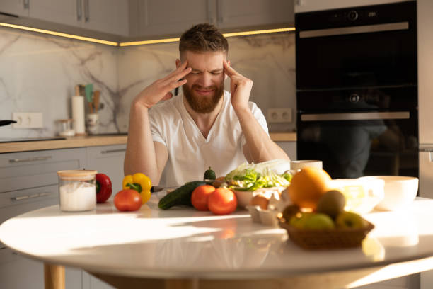 istock Young tired man with headache sitting at table 1328861857