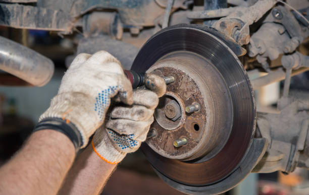 istock Gloved hands unscrew the rear rusted wheel hub with a screwdriver 1328865936