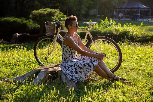 Young attractive woman sitting in the park after after a bike ride