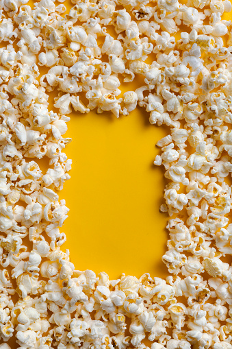 Frame popcorn yellow background top view.