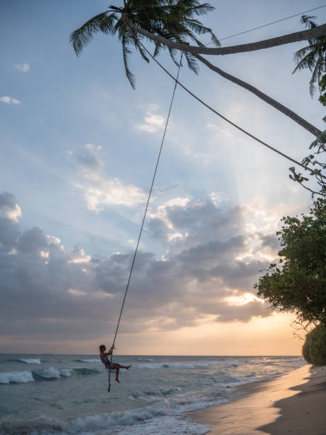 istock Man plays on rope swing above sea 1328871138