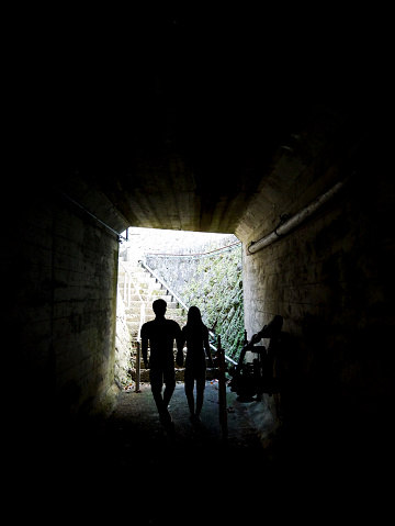 Young couple walking through a tunnel towards the light