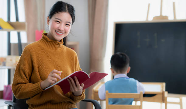 asian teacher at preschool helping children in class in class room - primary care imagens e fotografias de stock