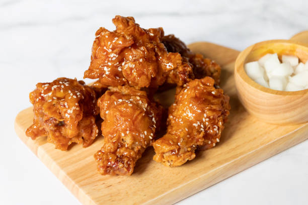 Deep fried chicken wing with spicy sauce in Korean style with pickled radish serve on wooden plate. stock photo