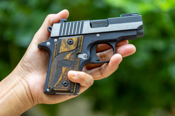 istock Small automatic handgun or conceal pistol in her hand on nature background 1328874279
