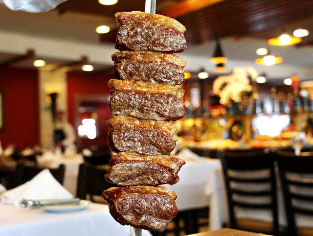 Picanha. Brazilian traditional steak in barbecue. Slices of grilled Picanha on a spit. Restaurant background Picanha. Brazilian traditional steak in barbecue. Slices of grilled Picanha on a spit. Restaurant background. brazilian bbq stock pictures, royalty-free photos & images