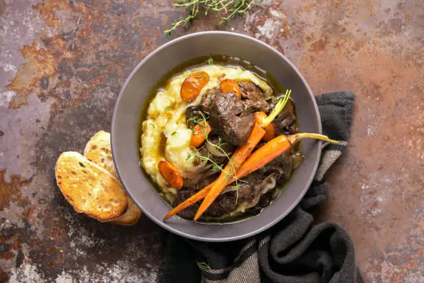 Beef bourguignon served in a rustic manner with smashed potatoes, top down view recipe concept
