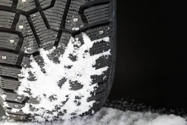 New winter tires in the snow, on the black background