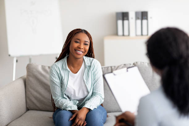successful therapy. young female client having consultation with psychologist, grateful for professional help at clinic - mental health stockfoto's en -beelden