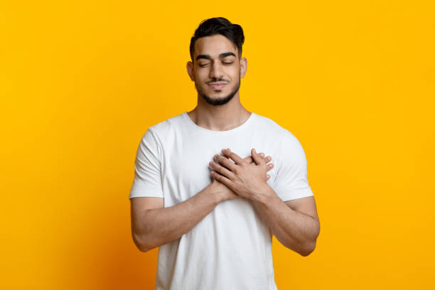 istock Peaceful arab guy with closed eyes holding hands on chest 1328879102
