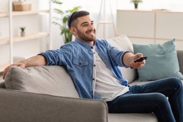 istock Happy jewish guy spending weekend watching tv 1328880353