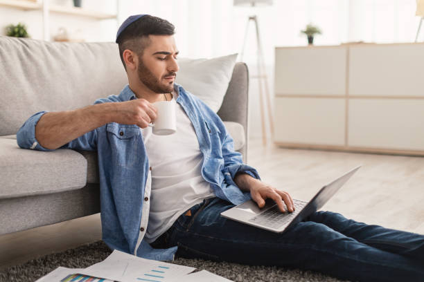 istock Serious jewish man watching video on pc, drinking hot coffee 1328880389