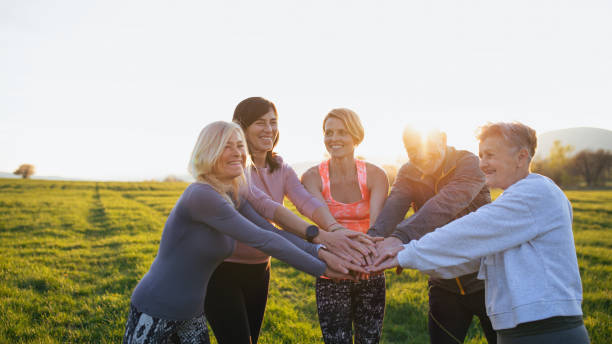 istock Group of seniors with sport instructor stacking hands together after exercise outdoors in nature at sunset. 1328880658