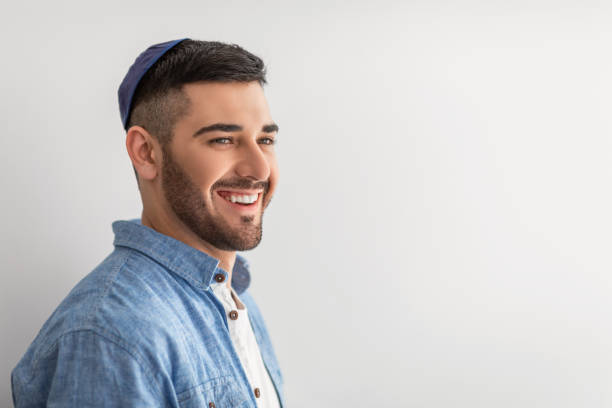 Closeup portrait of smiling jewish man in yarmulke Happy Person. Closeup portrait of handsome cheerful israeli guy posing at studio, smiling and looking aside, wearing yarmulke, posing isolated on light background wall, copy free space, advert banner yarmulke photos stock pictures, royalty-free photos & images