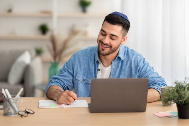 istock Smiling israeli man working on laptop at home 1328880733