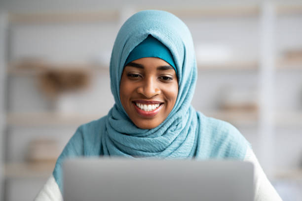 ラップトップを使用して青いヒジャーブで黒いイスラム教徒の女性のクローズアップショット - businesswoman black african descent studio shot ストックフォトと画像