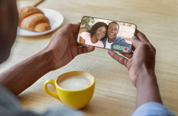 istock Remote communication concept. Young black guy using smartphone to talk to his friends online at urban cafe 1328881618