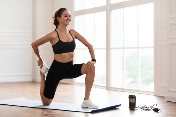 istock Young woman stretching leg exercising on yoga mat 1328882921