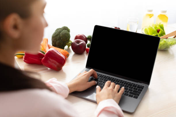 istock Woman using laptop with empty screen sitting at desk 1328883088
