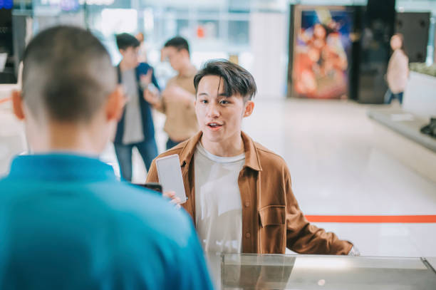 asian chinese young male audience  in front ticket counter buying movie tickets and  popcorns drink contactless payment before movie show time at movie theater cinema - ticket movie theater movie movie ticket imagens e fotografias de stock