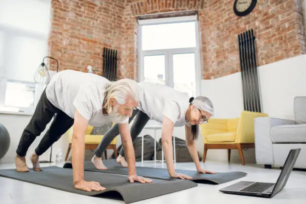 Photo of Mature couple using laptop for doing downward dog pose