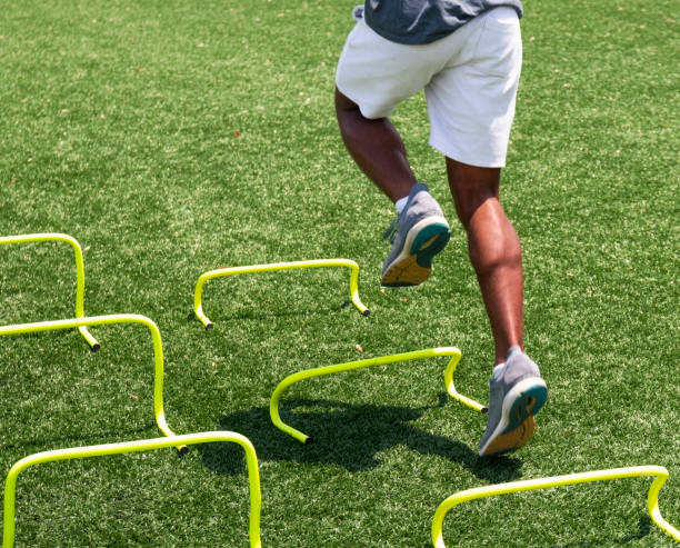 Legs of runner running over yellow mini hurdles A high school runner is running over yellow mini hurdles at track camp. sports training drill stock pictures, royalty-free photos & images