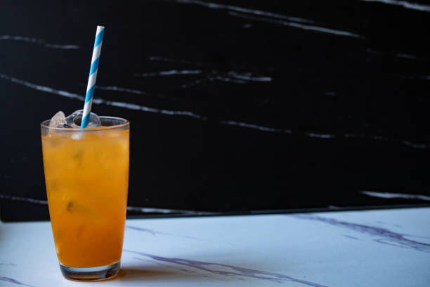 istock Orange juice in a transparent glass on a black background Copy space 1328888579