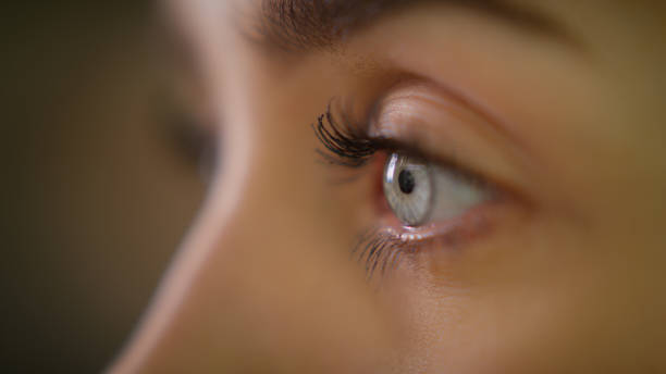 Extreme closeup on bright blue eye. Beautiful female face Female human eye details. Studio shot blinking stock pictures, royalty-free photos & images