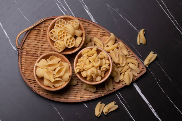 istock Raw pasta in a wooden cup on black marble background.Copy space 1328890429