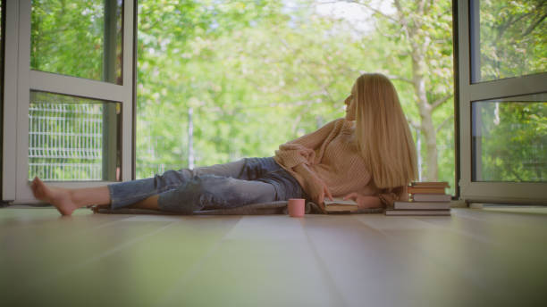 istock Self love time. Woman sitting by the open window and enjoying book 1328896285