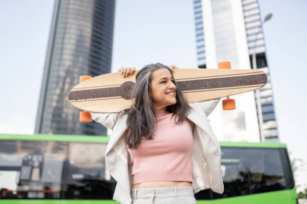 mujer de pelo bonito plateado con monopatín en la ciudad - cámara lenta fotografías e imágenes de stock