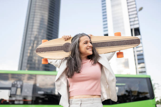 pretty silver haired woman with skateboard in the city pretty silver haired woman with skateboard in the city slow motion stock pictures, royalty-free photos & images