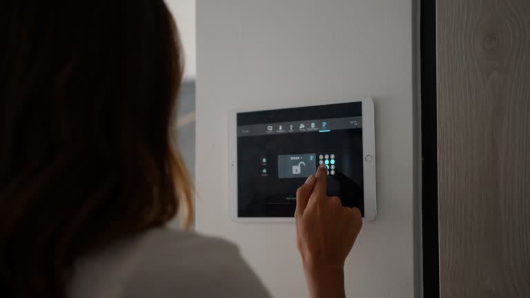 Latin American woman leaving her automated home activating the lock on digital tablet introducing the pin