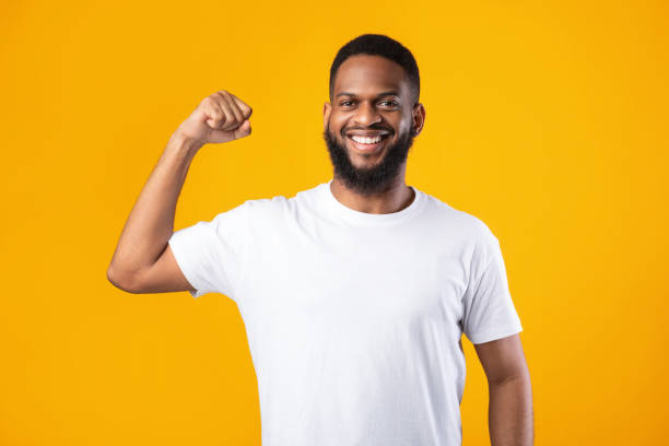 istock Cheerful Black Guy Showing Biceps Muscles Posing On Yellow Background 1328898127