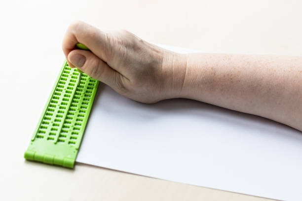 istock hand writes words in braille with slate and stylus 1328898202