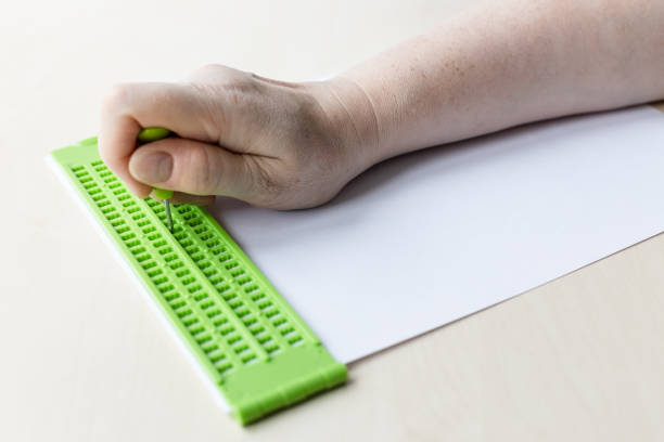 istock hand types words in braille with slate and stylus 1328898209